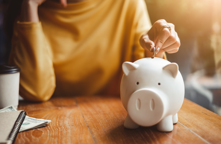 First home buyer adding an Australian gold coin into her savings piggy bank