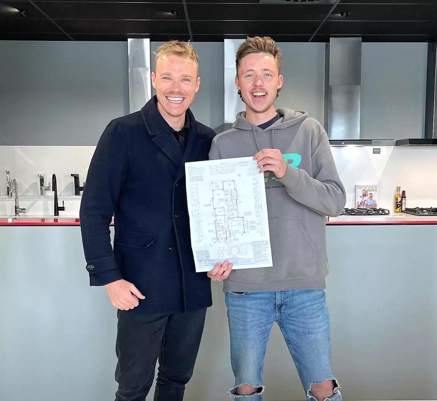 Jack Thornton with a male first home buyer smiling holding up a floorplan